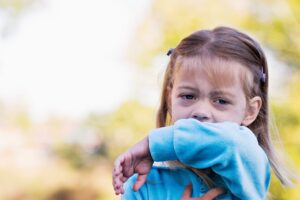 A little girl sneezes into the inside of her elbow for rsv and the common cold blog.
