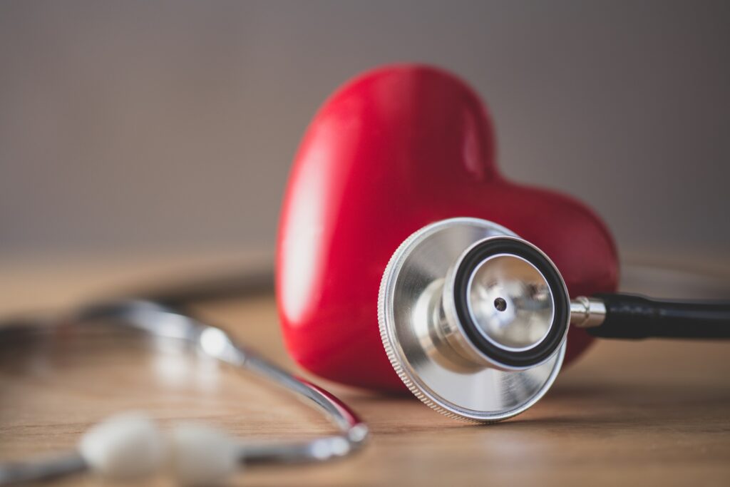 A plastic heart surrounded by a stethoscope announces American Heart Month for your heart health blog.