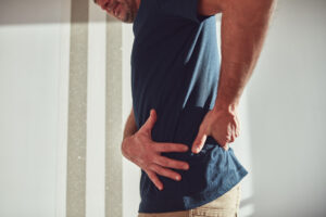 A man grasps his stomach and lower back for urgent-care-for-hernia blog.